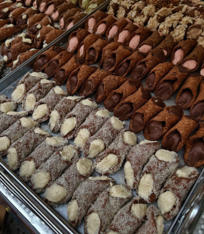 Trays of assorted Sicilian cannoli filled with sweet ricotta