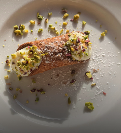 A pistachio-topped Sicilian cannolo dusted with icing sugar