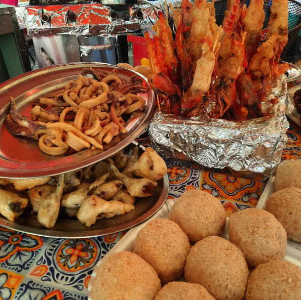 Fried Palermo street food: arancine, calamari and prawn skewers at a market stall